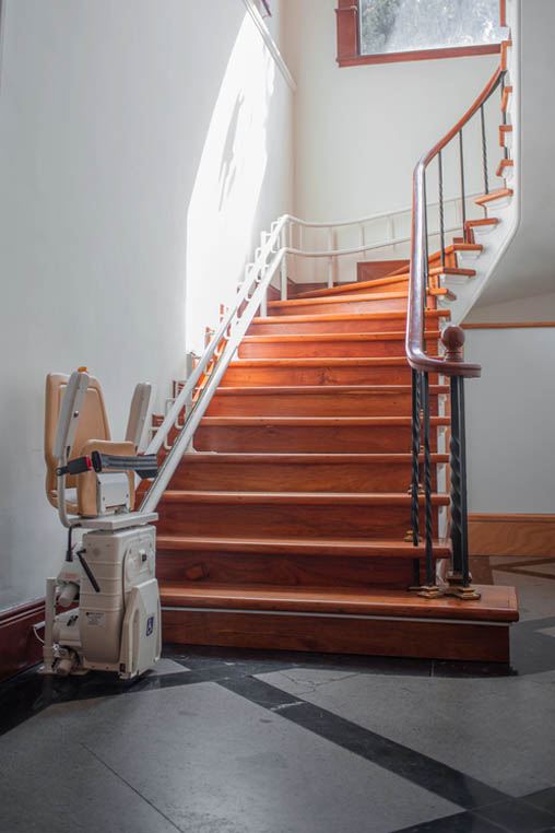 Fotografía de escalera curva con silla salvaescaleras curvo instalado.